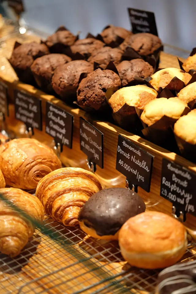 Croissants and muffins in a bakery case.