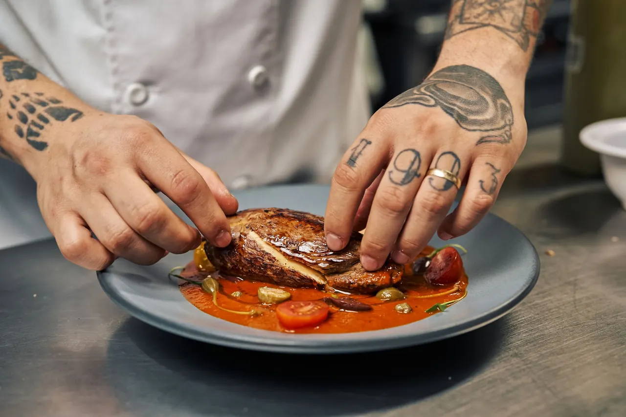 A chef plating a dish in a restaurant kitchen.