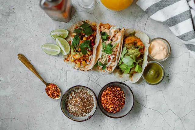 Street tacos with lime and salsas, top view.