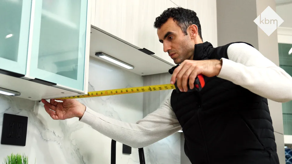A cabinet maker measuring a kitchen opening.