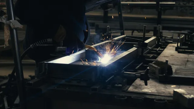 Gloved hands weld a metal frame held in a workbench jig.