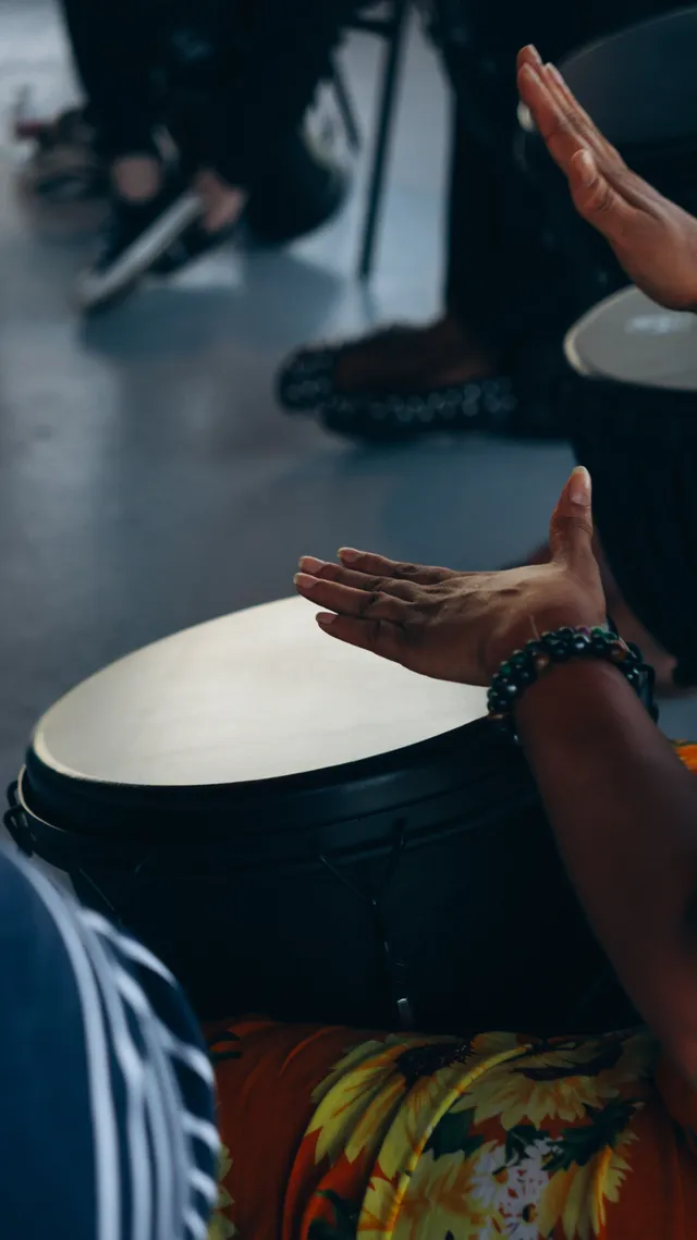 Hands playing a drum during a group music session.