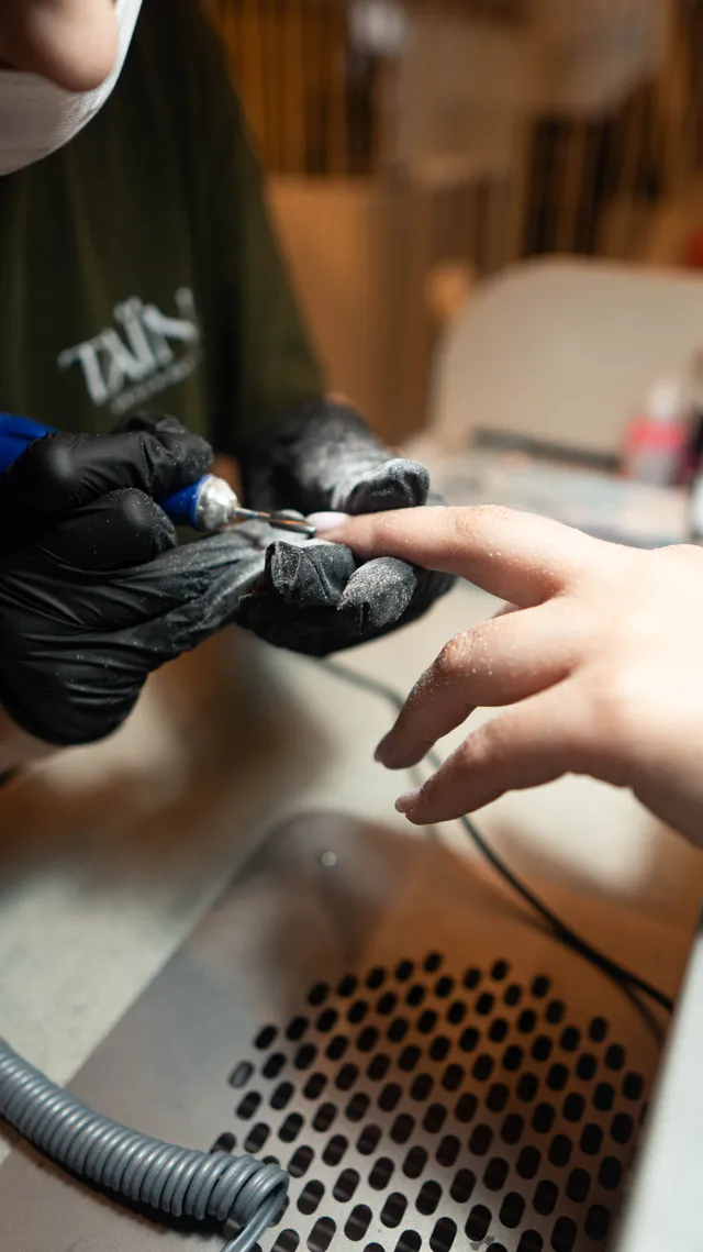 A nail technician works on a manicure.
